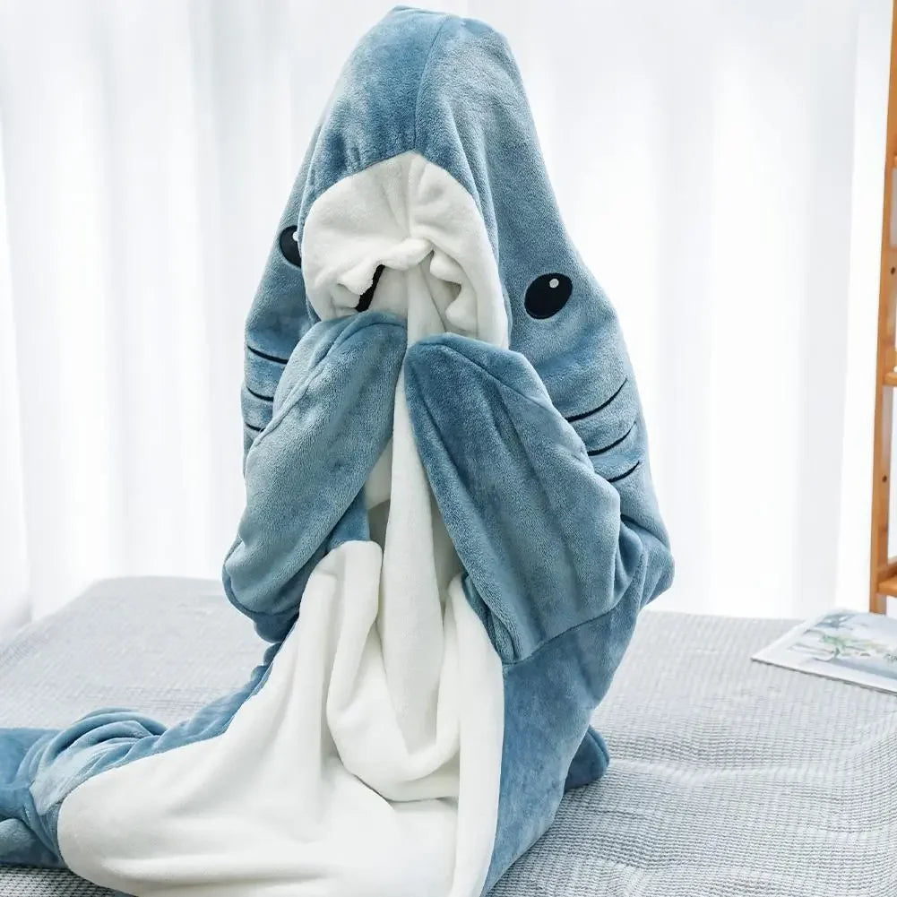 Shark-shaped plush blanket on a bed with a white curtain background
