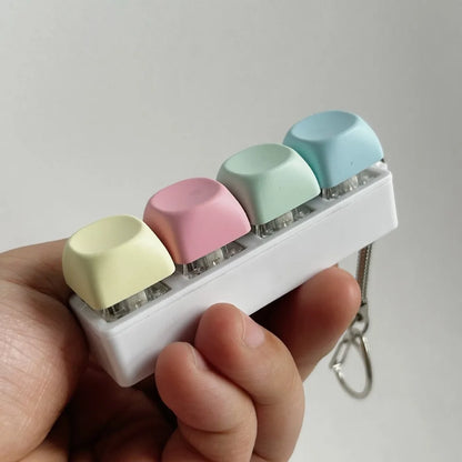 Small rectangular device with pastel-colored keys held by a hand against a plain background