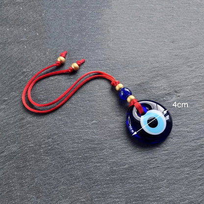 Blue evil eye charm with red string on a gray background