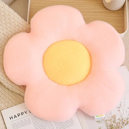 Flower-shaped pink cushion with a yellow center on a surface with a magazine underneath.