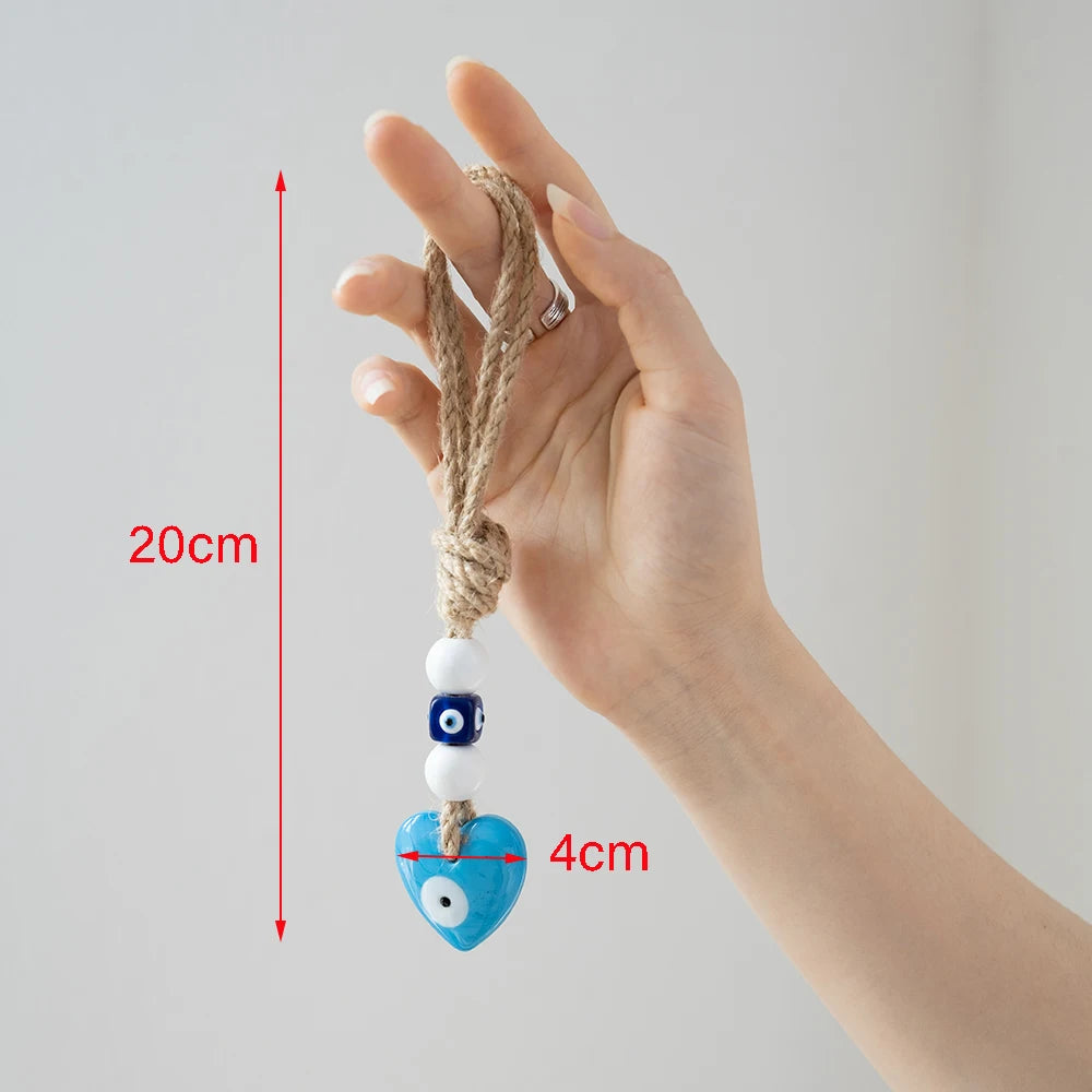 Hand holding a decorative item with a blue heart and white bead, measurement details shown.