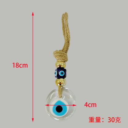 Evil eye charm with measurements on a gray background
