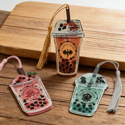 Three decorative bookmarks shaped like drinks with tassels on a wooden surface.