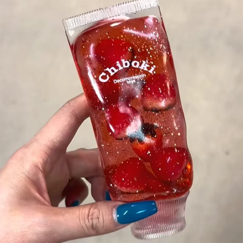 Hand holding a red gelatin dessert with visible brand name 'Chiboki' against a neutral background