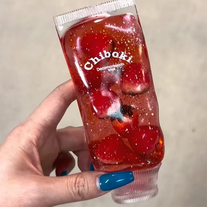 Hand holding a red gelatin dessert with visible brand name 'Chiboki' against a neutral background