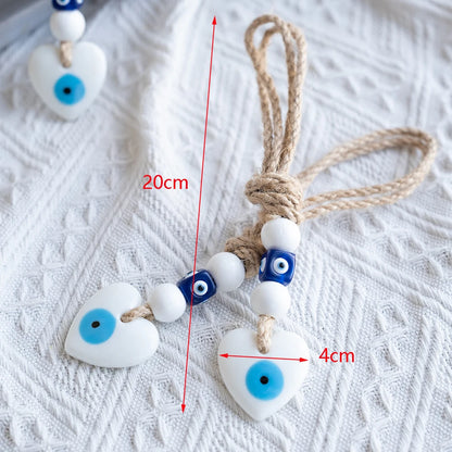 Heart-shaped evil eye charms with measurement markings on a textured white surface