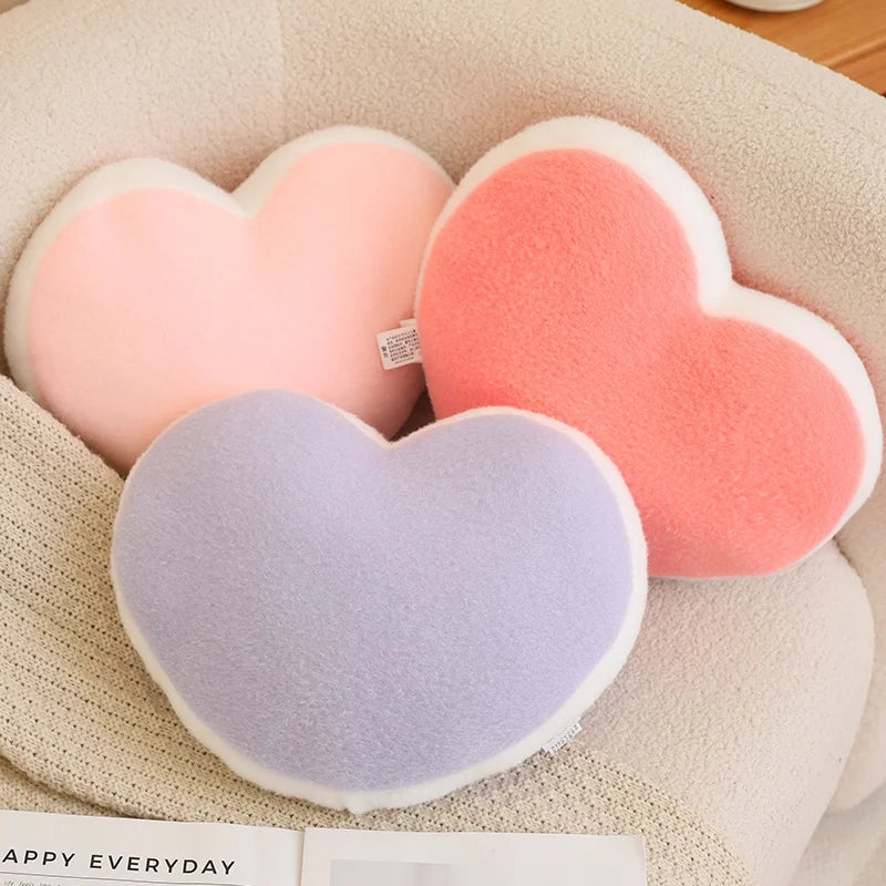 Heart-shaped cushions in pink and gray on a textured surface with 'Happy Everyday' branding.