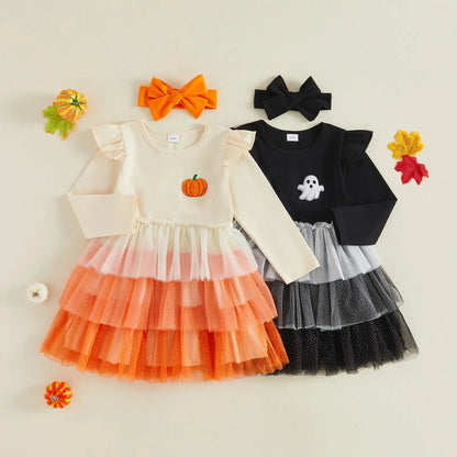 Two toddler girls' Halloween dresses laid flat on a light beige background, each with a matching bow headband. The front dress is cream with a layered orange-to-peach tulle skirt and a pumpkin applique; the back dress is black with a layered gray-and-white tulle skirt and a ghost applique.