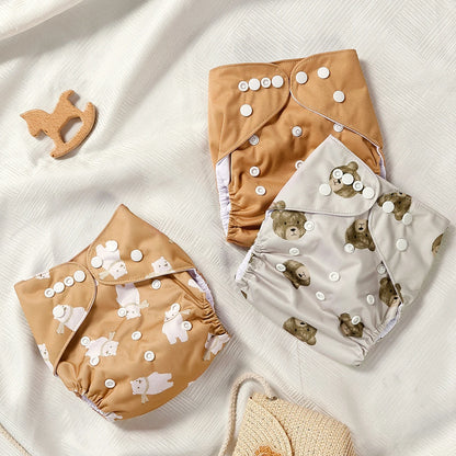 Two baby cloth diapers with bear pattern on a white fabric background