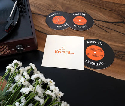 Record player with 'You're My Favorite' coasters and a card on a wooden surface.