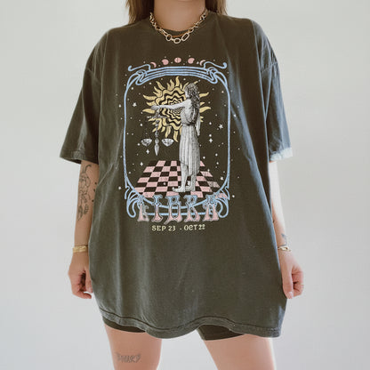 Person wearing a t-shirt with a graphic design of a tarot card-style illustration.