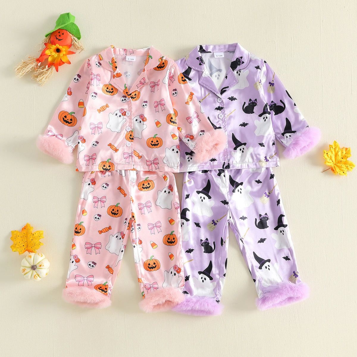 Two children's pajama sets laid flat on a light beige background. One set is pink with Halloween prints including pumpkins, ghosts, and bows, with fuzzy pink cuffs.