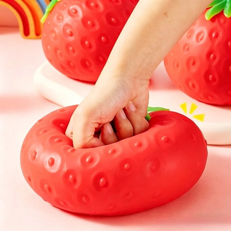 Hand pressing a red strawberry-shaped stress ball with a colorful background