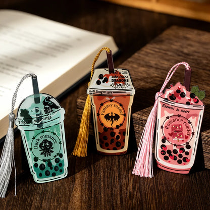 Three decorative bookmarks shaped like drinks on a wooden surface with an open book.
