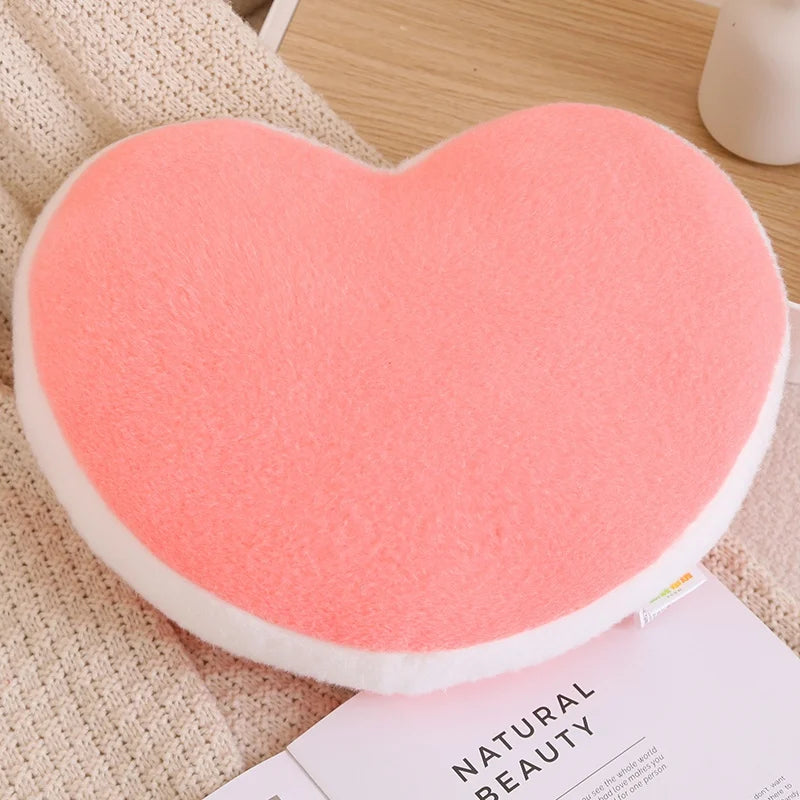Heart-shaped pink cushion on a textured surface with a magazine underneath