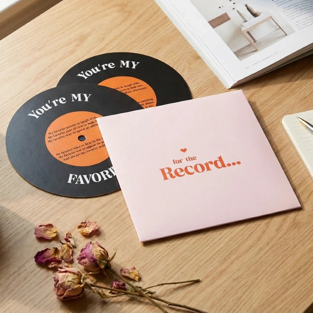 Two vinyl records with 'You're My Favorite' text and a card on a wooden surface with dried flowers.