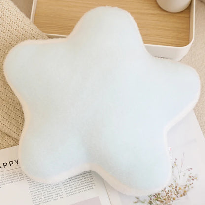 Star-shaped white pillow on a surface with a book and cup in the background