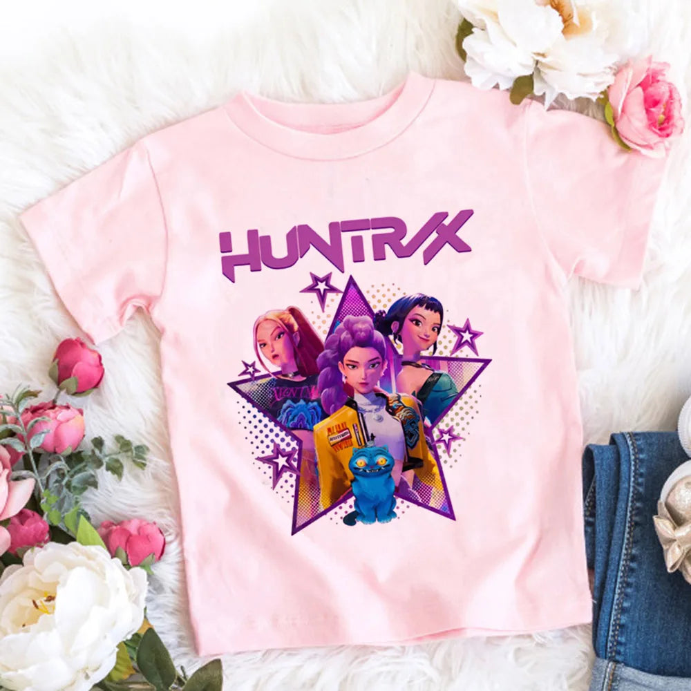 Pink t-shirt with 'HUNTRAX' design on a white surface with flowers and denim jeans.