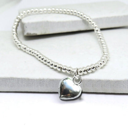 Silver beaded bracelet with a heart charm on a white background