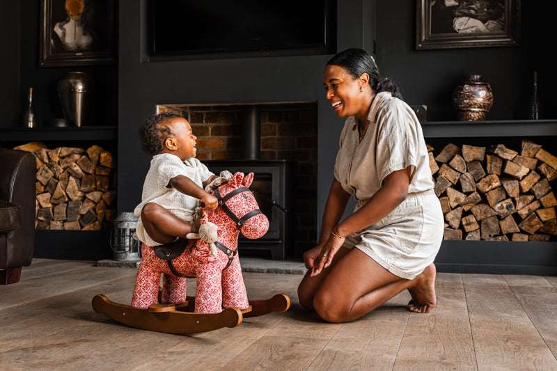 Woman and child playing with a rocking horse in a cozy living room.