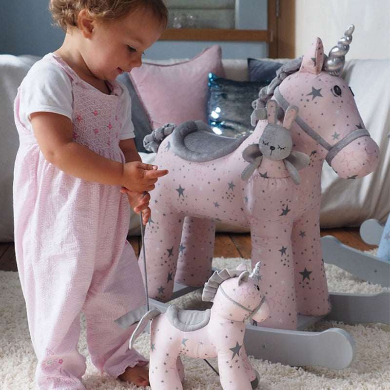 Child playing with a pink unicorn toy in a cozy living room.