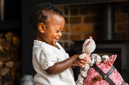 Child playing with a toy horse in front of a stone fireplace