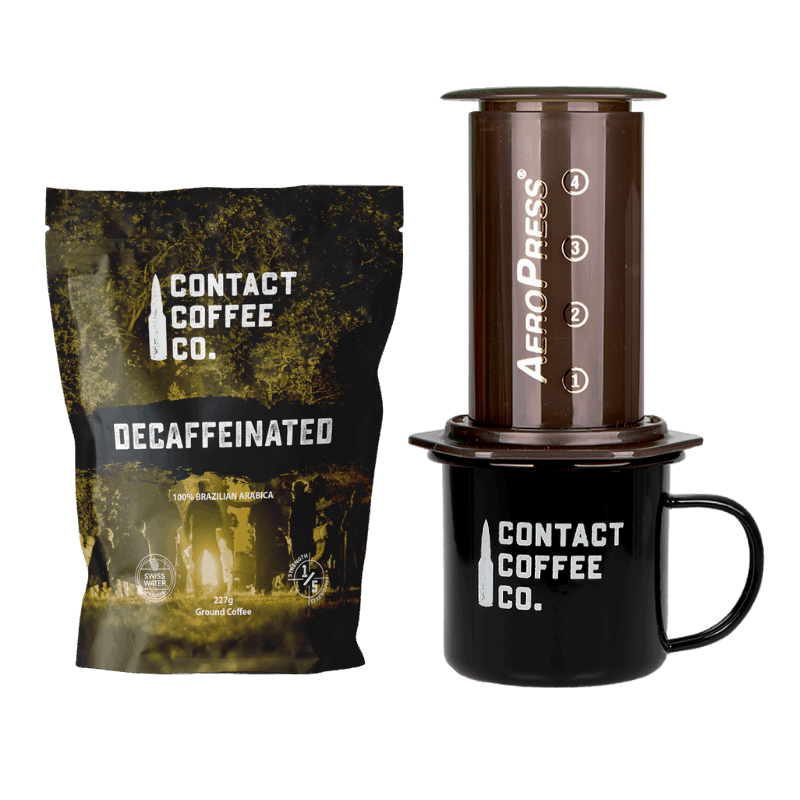 Decaffeinated coffee package, AeroPress coffee maker, and Contact Coffee Co. mug on a white background