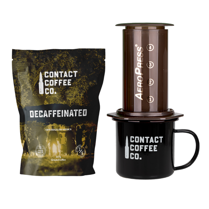 Decaffeinated coffee package, AeroPress coffee maker, and Contact Coffee Co. mug on a white background