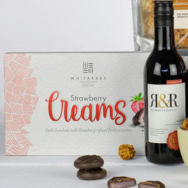 Bottle of R&R Chocolates with a box of Whitaker's Strawberry Creams on a white background