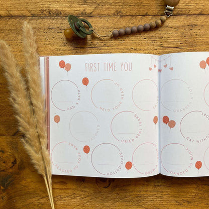 Open book with printed content on a wooden surface with a pacifier and dried grass.