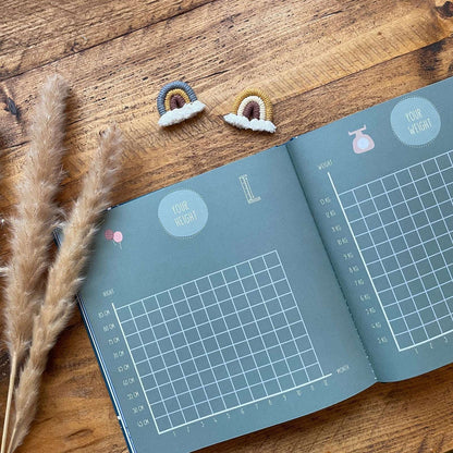Open book with weight measurement chart on a wooden surface with decorative elements.