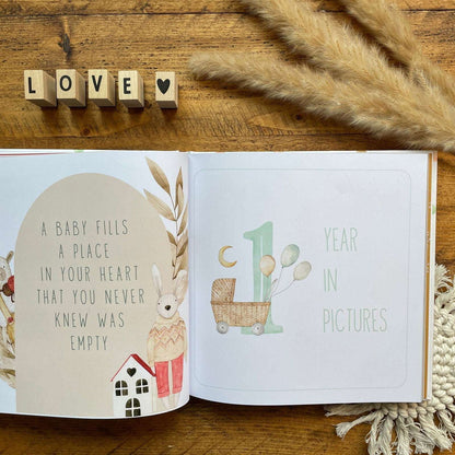 Open book with baby milestone illustrations on a wooden surface with decorative elements.