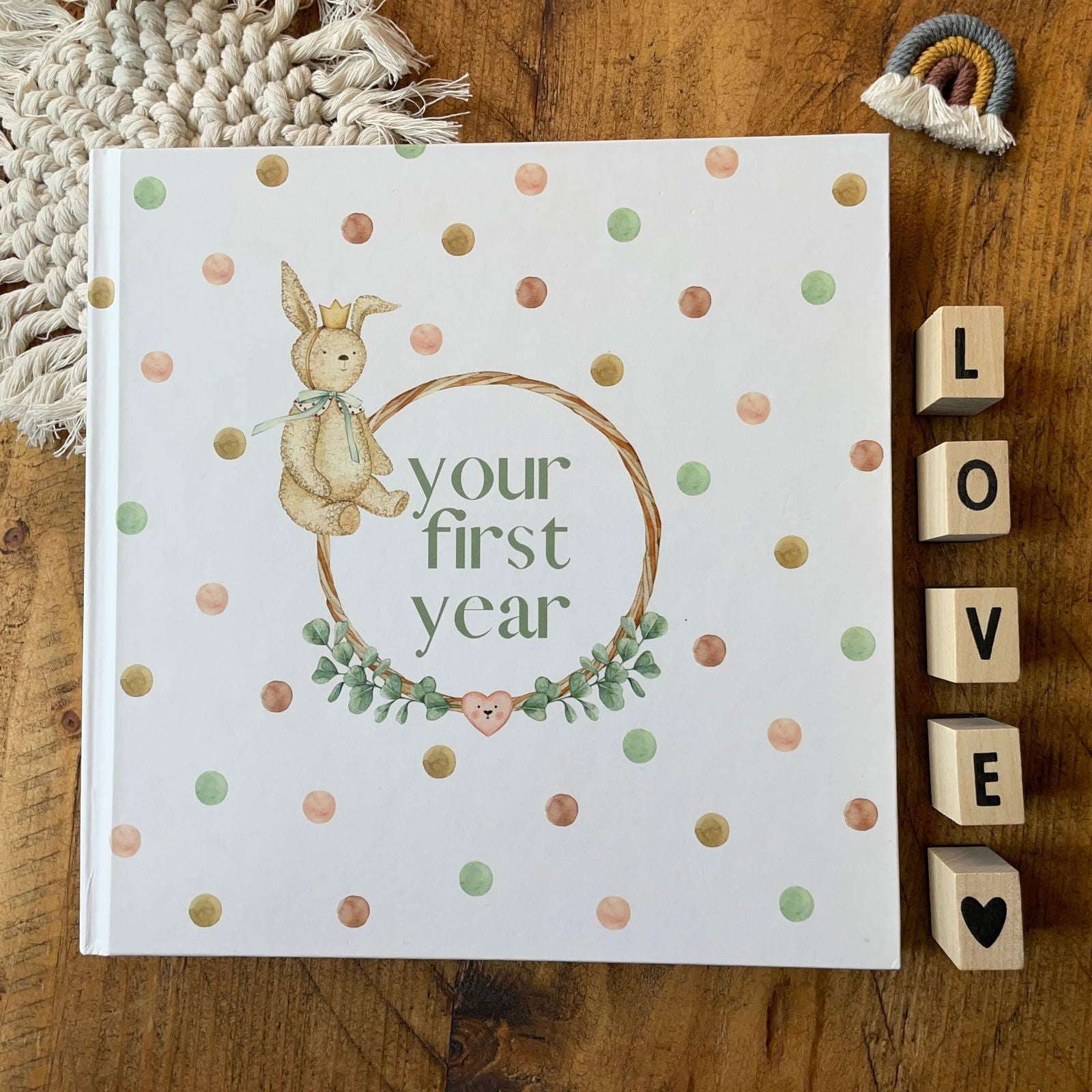 Book titled 'your first year' with a bunny illustration on a wooden surface with decorative elements.