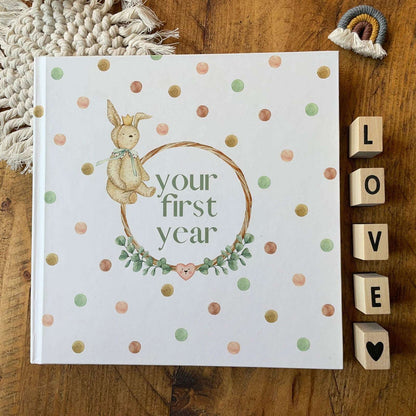 Book titled 'your first year' with a bunny illustration on a wooden surface with decorative elements.
