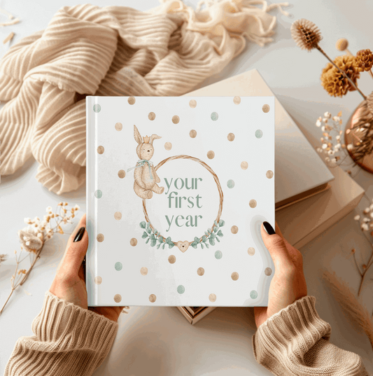 Book titled 'Your First Year' held by hands with polka dot cover on a soft surface.