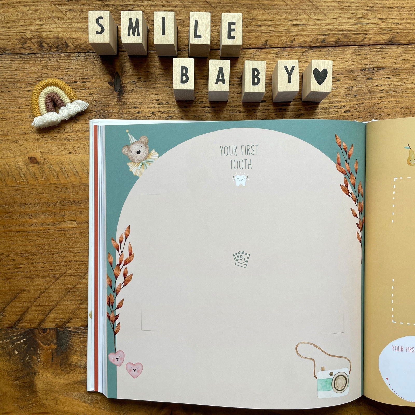 Open book with baby-themed pages on a wooden surface, featuring the text 'SMILE BABY' above.