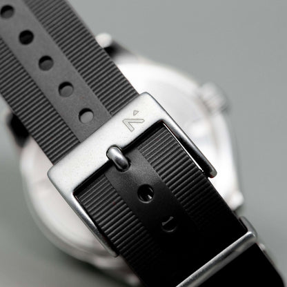 Close-up of a watch with a black strap and silver buckle on a gray background