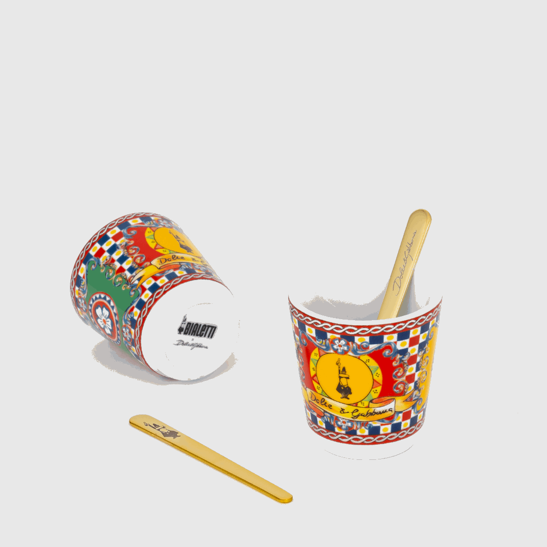 Two colorful ceramic cups with a wooden spoon on a light gray background
