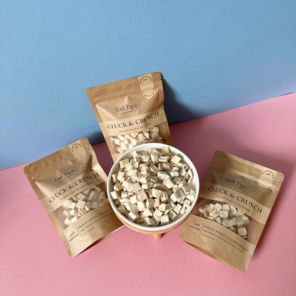 Tail Tips Cluck & Crunch treats in packaging on a pink and blue background