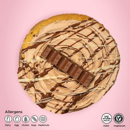 Round dessert with chocolate drizzle and a KitKat bar on a pink background, featuring allergen information.