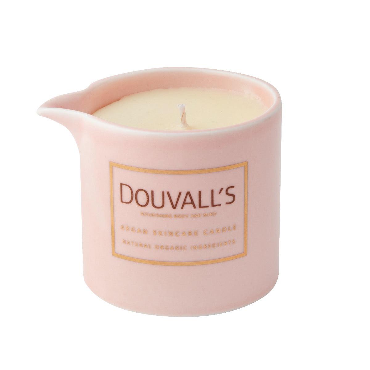 Pink ceramic candle holder with a lit candle inside on a white background, featuring the brand 'Douvall's'.