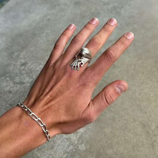 Hand wearing a silver ring and bracelet on a neutral background