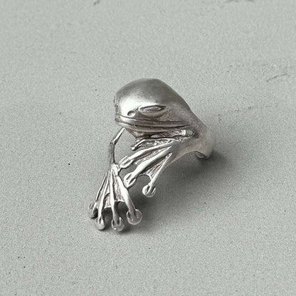 Silver frog ring on a light gray background
