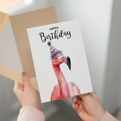 Greeting card with a flamingo and 'Happy Birthday' text held by hands.