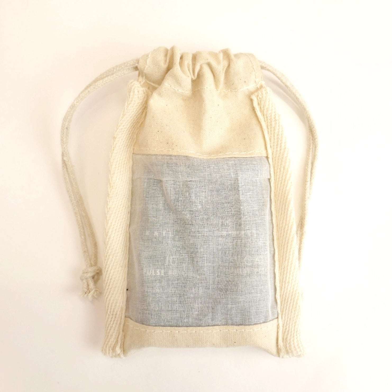 Beige drawstring bag with a gray interior on a light beige background