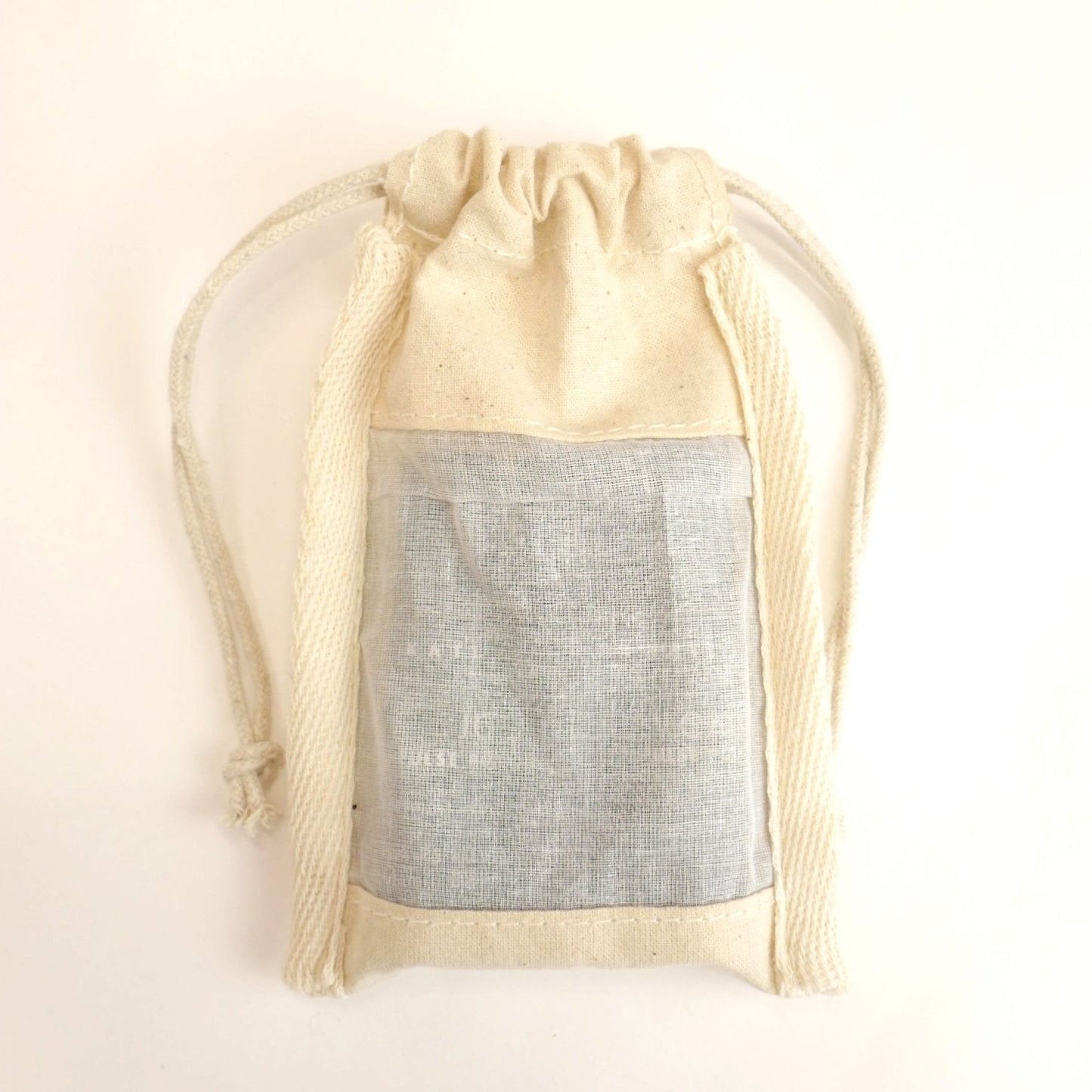 Beige drawstring bag with a gray interior on a light beige background