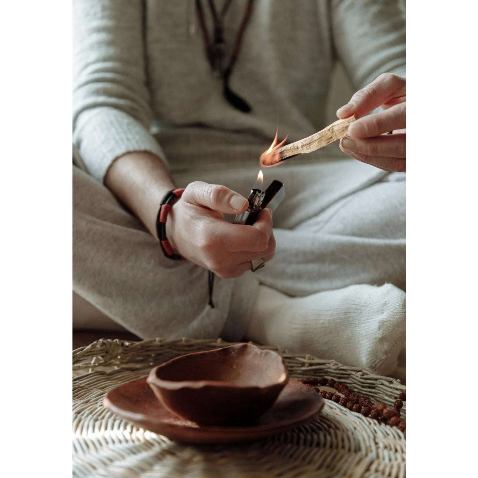 Person lighting a wooden stick with a lighter on a textured surface