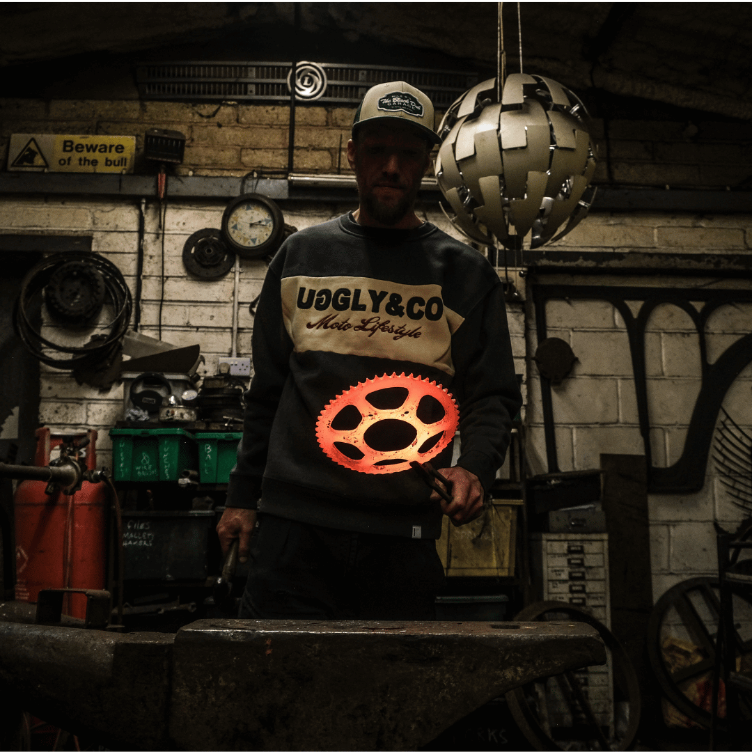 Person wearing a 'UGLY&CO' sweatshirt in a workshop setting