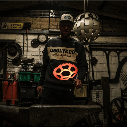 Person wearing a 'UGLY&CO' sweatshirt in a workshop setting