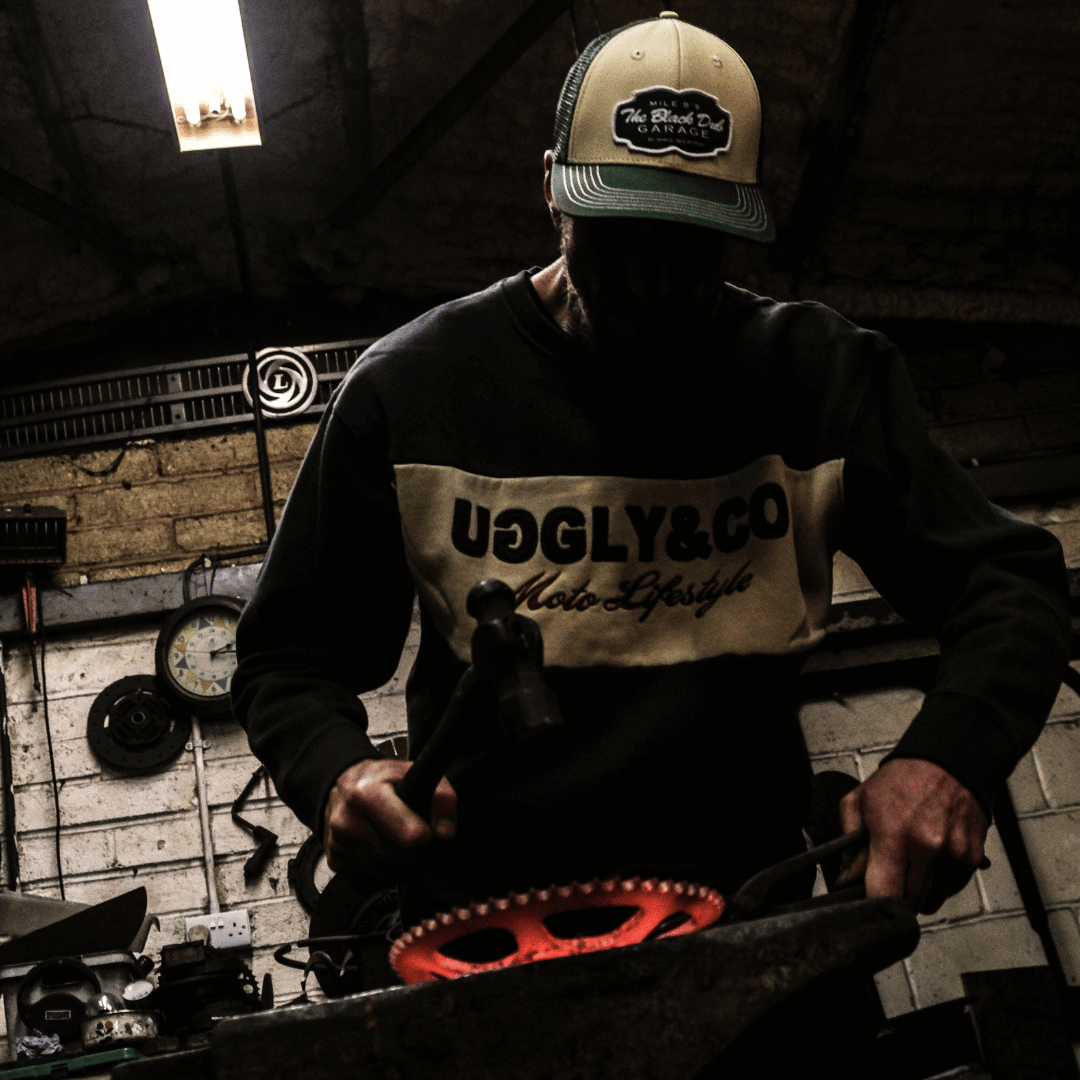 Person wearing a cap and sweatshirt with visible branding in a workshop setting